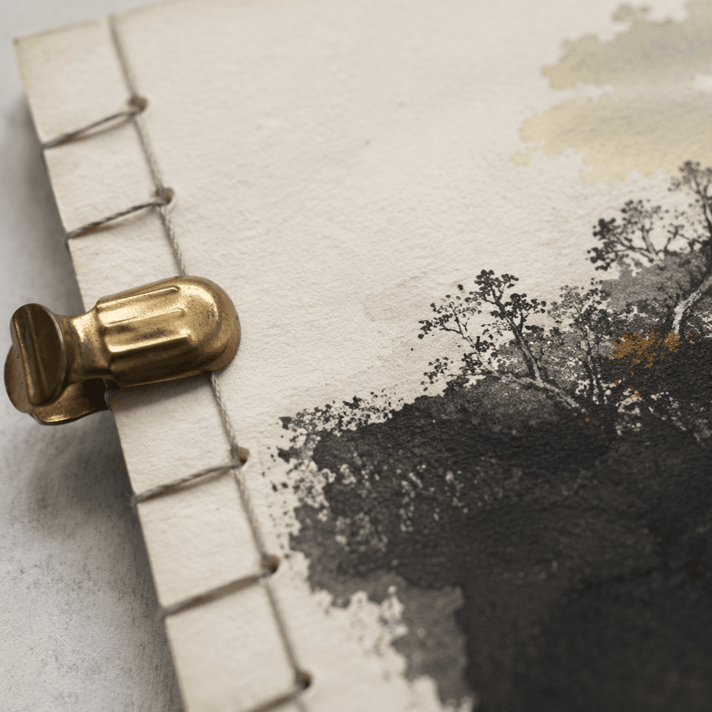 Close detail of paper texture, stitched binding and a brass clip